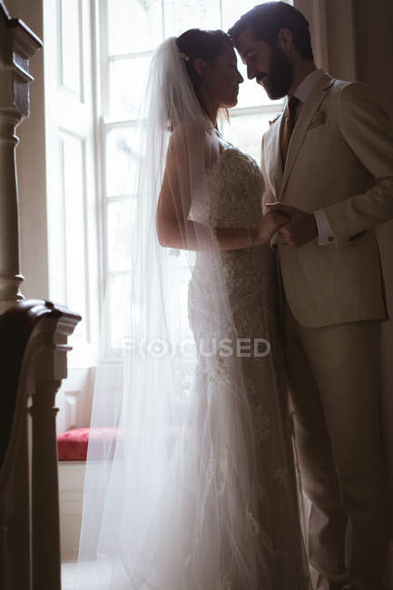 Жених и невеста стоят лицом к лицу на лестнице дома — стоковое фото