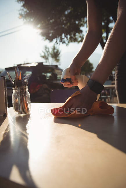 Sección media de la mesa de limpieza del trabajador en la cafetería al aire libre - foto de stock