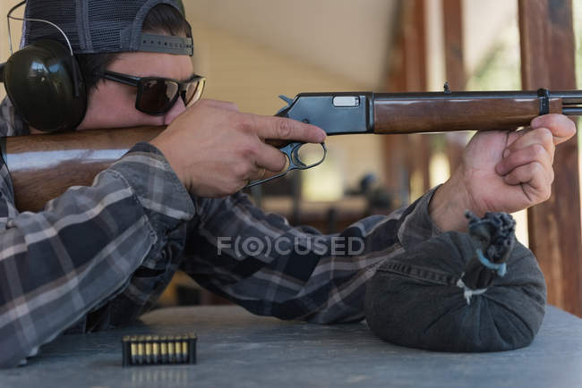 Close-up of man aiming shotgun at target in shooting range — Stock Photo