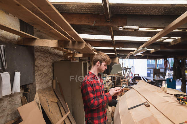 Молодой плотник, использующий цифровые планшеты в мастерской — стоковое фото