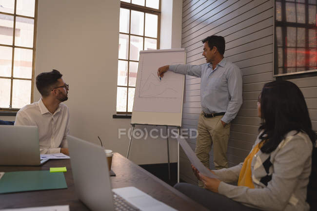 Businessman giving chart presentation on whiteboard in conference room at office. — Stock Photo