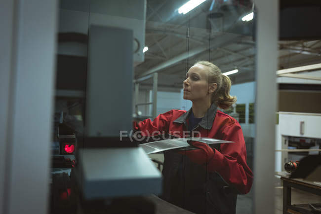 Жінка-працівник перевіряє машину на заводі — стокове фото