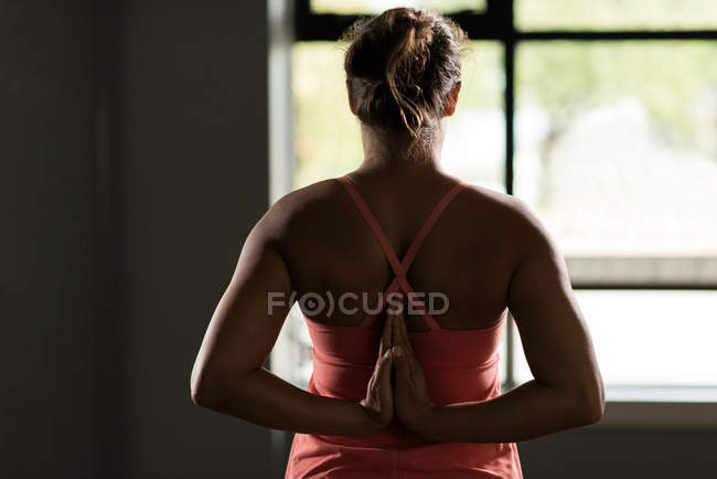 Rear view of woman practicing yoga in fitness studio. — Stock Photo
