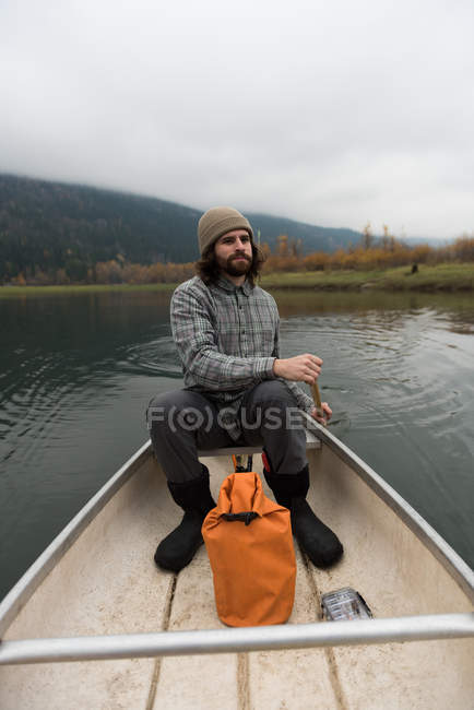 Fisherman oaring canoe in the middle of the lake — Stock Photo