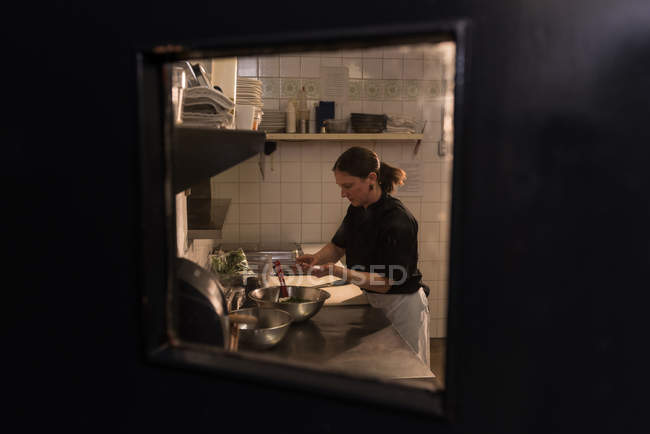 Chef concentrado trabajando en la cocina comercial - foto de stock