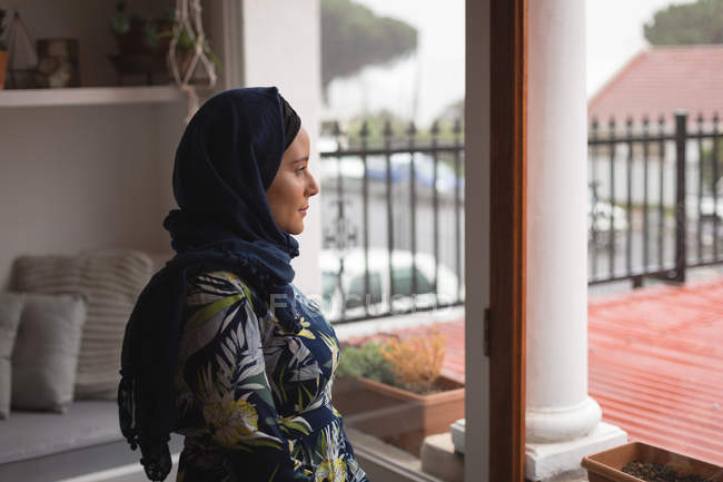 Mulher muçulmana atenciosa olhando pela janela — Fotografia de Stock