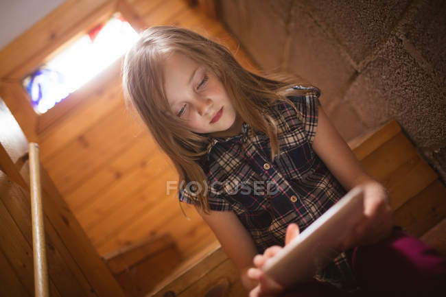 Fille mignonne en utilisant la tablette sur l'escalier à la maison — Photo de stock