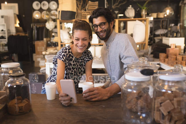 Пара, делающая селфи с мобильным телефоном у стойки в кафе — стоковое фото