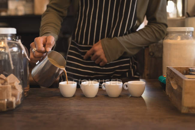 Бариста наливает кофе в чашки за стойкой в кафе — стоковое фото