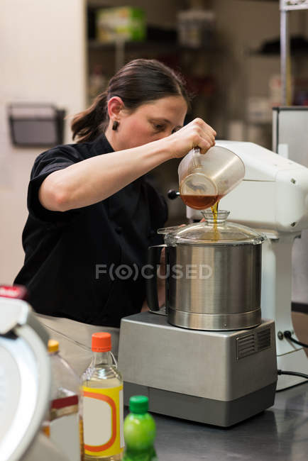 Chef versando olio commestibile in un macinino in cucina commerciale — Foto stock