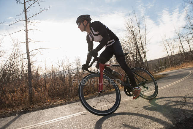 Байкер верхом на горном велосипеде по дороге в солнечный день — стоковое фото