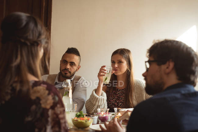 Amigos interactuando mientras comen en la mesa - foto de stock