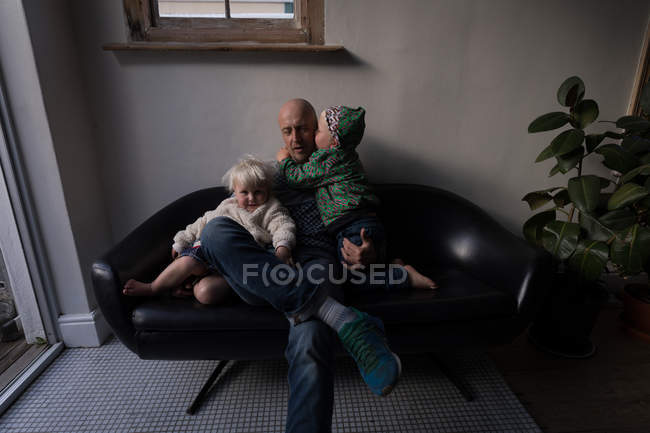 Vater spielt mit Kindern im heimischen Wohnzimmer auf Sofa. — Stockfoto