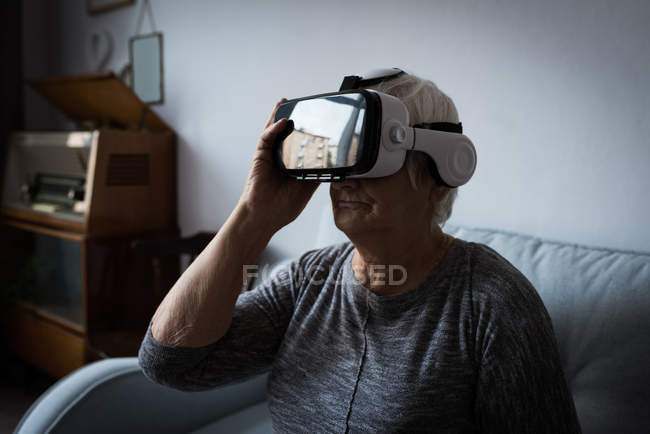Senior woman using virtual reality headset in living room at home — Stock Photo
