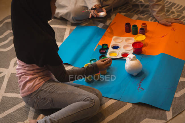Musulmana chica y su madre haciendo acuarela pintura en casa - foto de stock