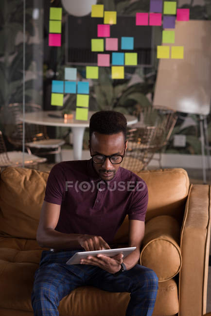 Executivo de escritório masculino usando tablet digital no sofá no escritório criativo — Fotografia de Stock