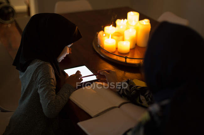 Mujer musulmana ayudando a su hija con los deberes en casa - foto de stock