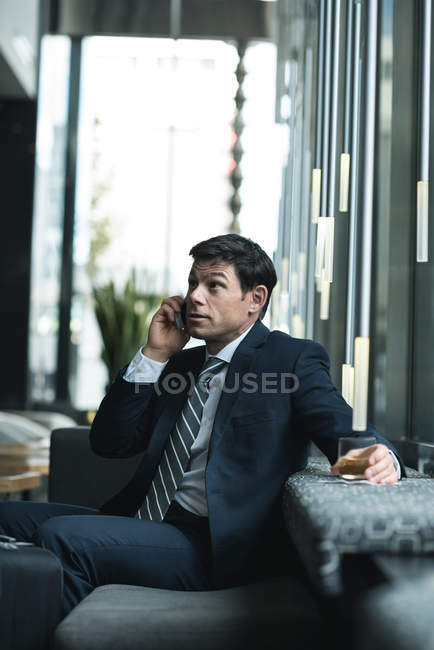 Businessman talking on mobile phone in office lobby — Stock Photo