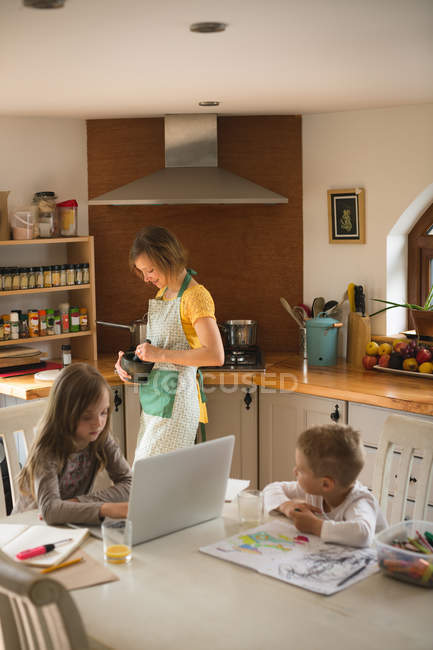 Дівчина з родиною, використовуючи ноутбук кухні в домашніх умовах — стокове фото