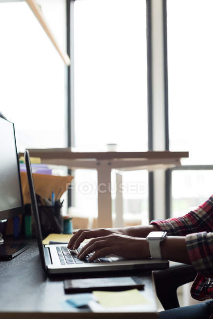 Female executive using laptop on desk in office — Stock Photo