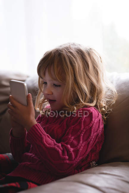 Дівчина використовує мобільний телефон у вітальні вдома — стокове фото