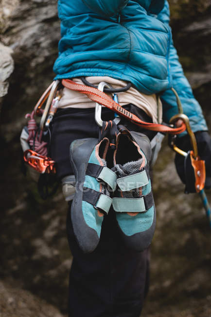 Средняя часть альпиниста, стоящего с обувью для скалолазания, прикрепленной к ремню — стоковое фото