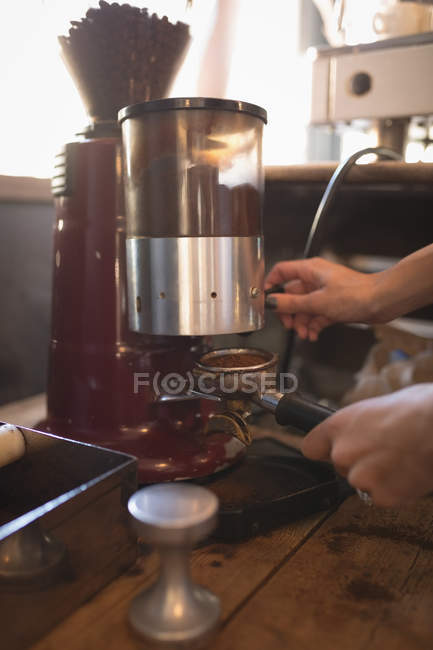 Barista broyage des grains de café dans un café — Photo de stock