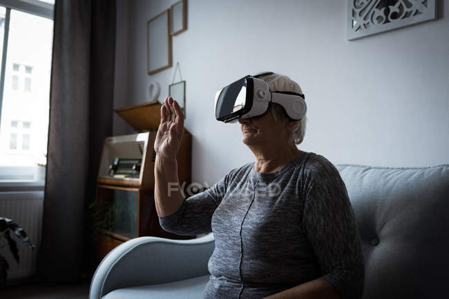 Senior woman using virtual reality headset in living room at home — Stock Photo