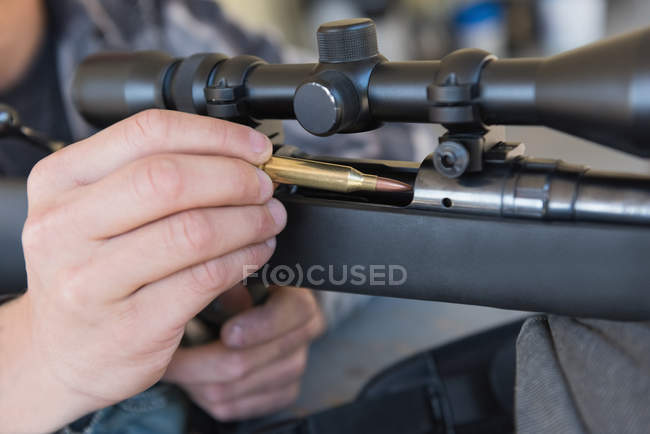 Крупним планом людина заряджає кулю в снайперську гвинтівку — стокове фото