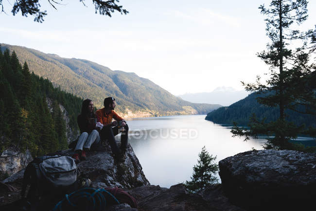 Coppia seduta pacificamente sulla roccia vicino al lago — Foto stock