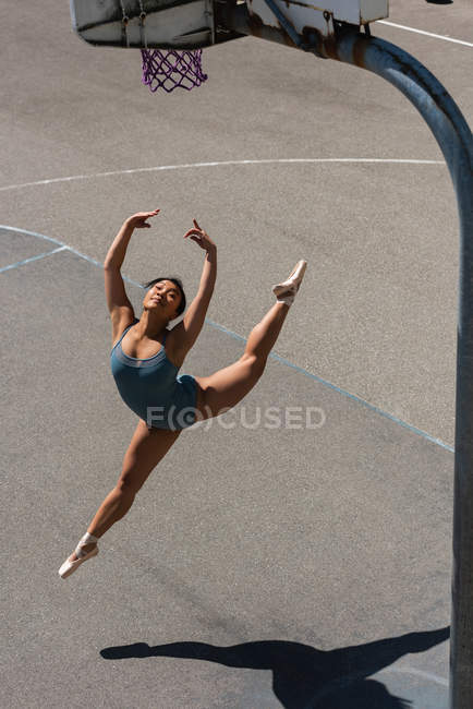 Молода балерина танцює на баскетбольному майданчику — стокове фото