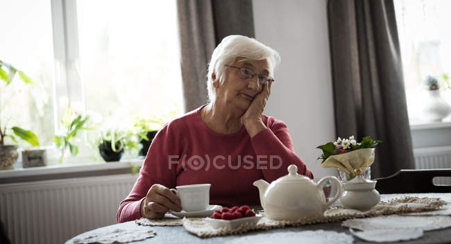 Продуманий старший жінка мислення у вітальні на дому — стокове фото
