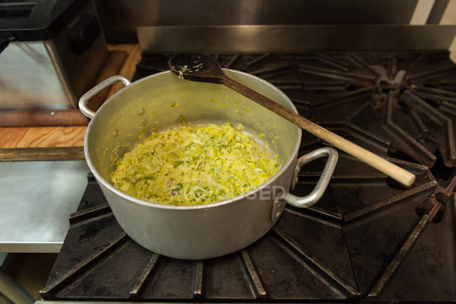 Close-up of wooden spoon with cooked vegetable in the pot — Stock Photo