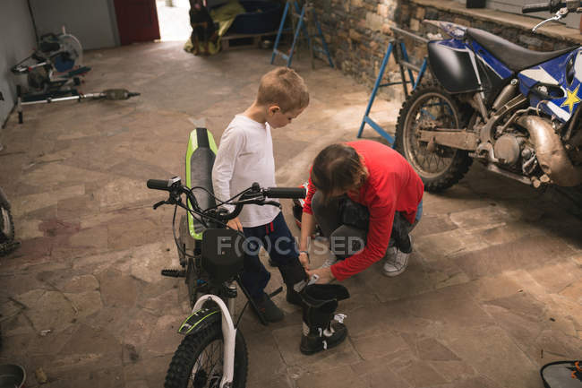 Мама готовит сына к поездке на велосипеде в гараж — стоковое фото
