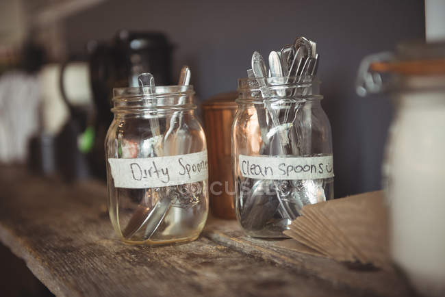 Clean and dirty spoons in jar on table — Stock Photo