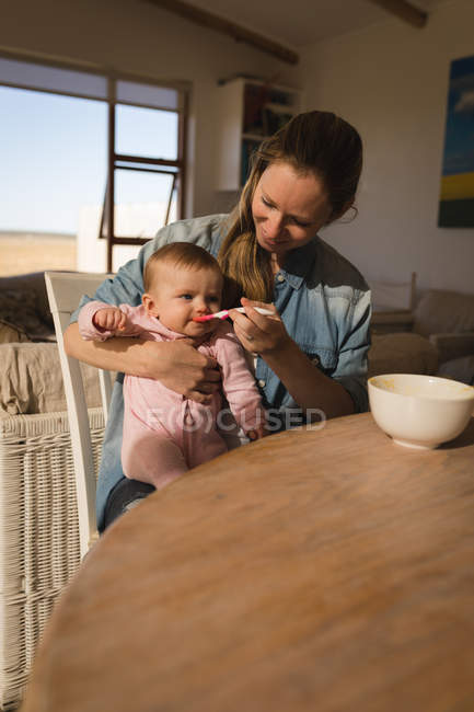 Mère nourrissant bébé garçon à table à la maison . — Photo de stock