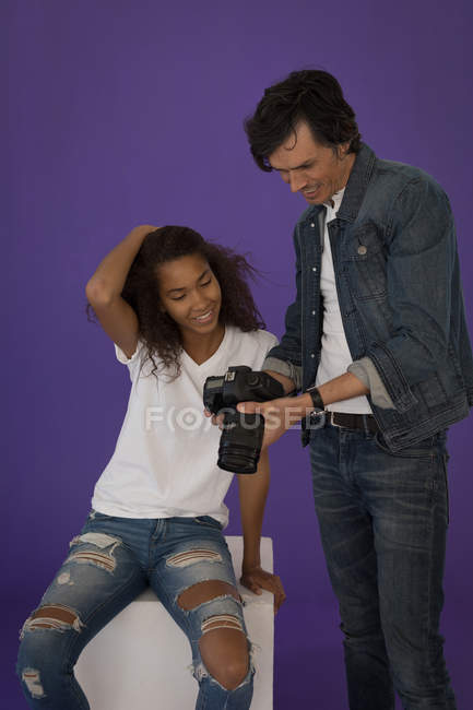 Fotógrafo mostrando fotos a modelo de moda en cámara digital en estudio - foto de stock