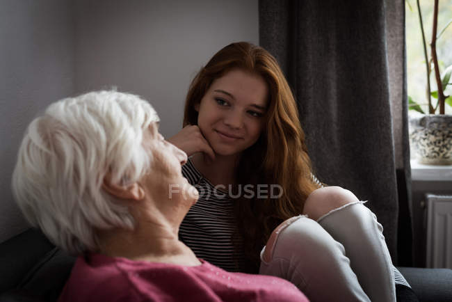 Granddaughter interacting with grandmother in living room at home — Stock Photo