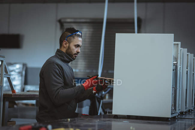 Trabalhador masculino verificando uma máquina na fábrica — Fotografia de Stock