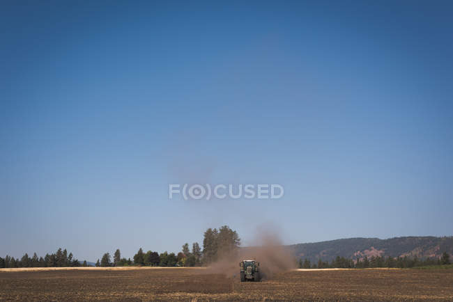 Трактор вспахивает поле в солнечный день — стоковое фото