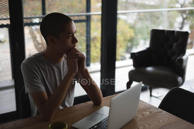 Nachdenklicher junger Mann benutzt Laptop zu Hause — Stockfoto