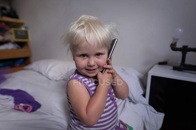 Toddler girl talking on mobile phone in bedroom at home. — Stock Photo