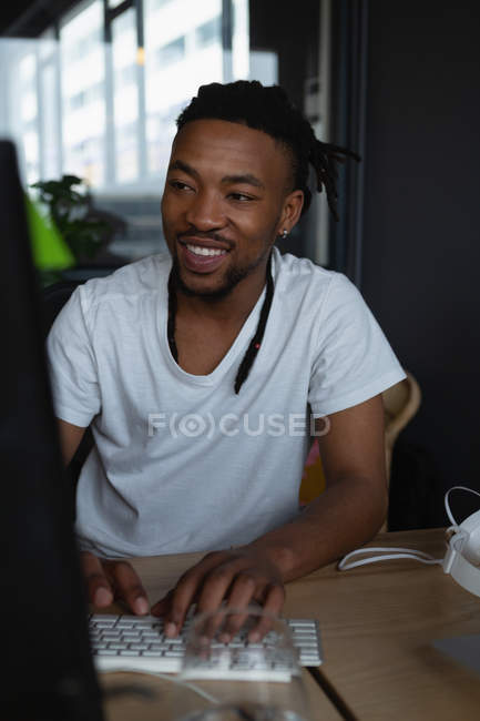 Sonriente ejecutivo masculino trabajando en el escritorio en la oficina . - foto de stock