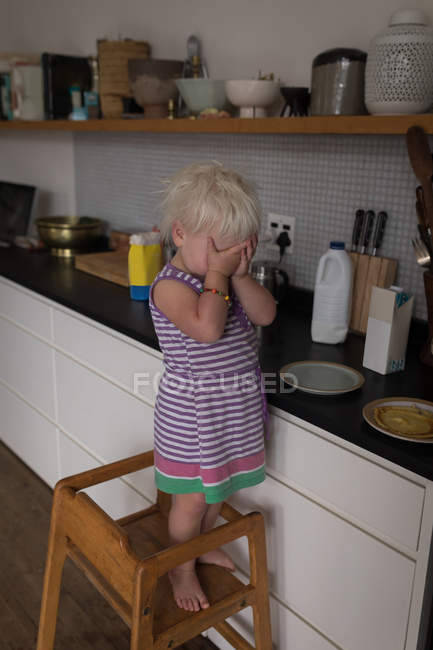 Petite fille debout sur la chaise dans la cuisine à la maison . — Photo de stock