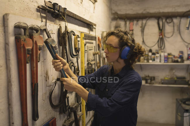 Femme ouvrière tenant une clé à molette dans un atelier — Photo de stock