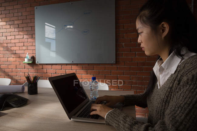 Female executive using laptop in conference room at office. — Stock Photo