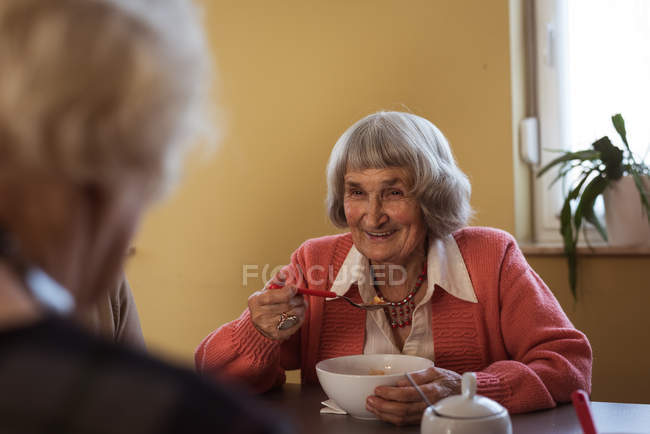 Усміхнені старші друзі взаємодіють під час сніданку в будинку престарілих — стокове фото