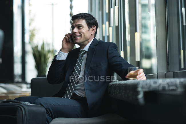Businessman talking on mobile phone in office lobby — Stock Photo