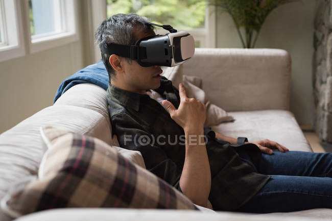 Uomo che utilizza cuffie realtà virtuale in soggiorno a casa — Foto stock