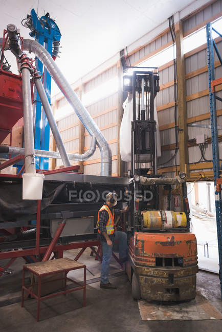 Man lifting sack of grains with forklift in factory — Stock Photo